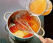 Broth being poured into the mixture of raisin sauce and pieces of ox tongue