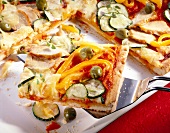 Close-up of pizza with pepper, green olives and chicken breast on spatula