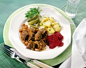 Onion meat with potatoes, beetroot, cucumber and parsley in plate