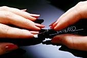 Close-up of woman applying nail corrector pen on her fingernails, step 1