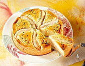 Banana cake with almonds decorated with whole bananas and a slice on spatula