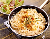 Spaetzle noodles with cheese and onions in saucepan