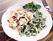 Spinach noodles with mushroom sauce and coriander on plate