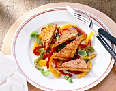 Fried tofu with red, yellow and green peppers on plate