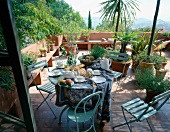 gedeckter Frühstückstisch auf einer Terrasse mit vielen Grünpflanzen