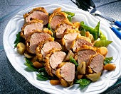 Pork fillet with potato crust, sugar peas, onions and carrots in serving dish