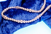 Close-up of pearl necklace on blue velvet cloth