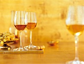 Drei Gläser Wein, daneben Wein- trauben, oranger Hintergrund