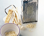 Grated and sliced horseradish in pot with grater