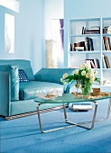 blauer Ledersessel in blauem Zimmer Bücherregal, Glastisch, Blumenvase