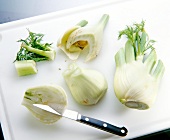Removing stems and green of fennel bulb on chopping board
