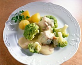 Potatoes and green cauliflower with ham and melted cheese sauce on plate