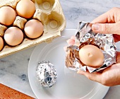 Wrapping egg with damaged shell in aluminium foil