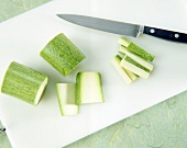 Sliced zucchini with kitchen knife on white chopping board
