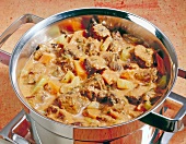 Oxtail stew being prepared in pot with carrots and celery