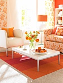 Wohnzimmer mit hellem Sessel und Sofa, Teppich in orange