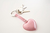 Key pendant with pink heart on white background