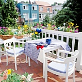 Balkon mit weissen Gartenmöbeln und mit vielen bunten Blumen bepflanzt