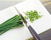 Chives being chopped in small rings on chopping board