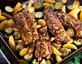 Close-up of pork ribs with herbs, potatoes and zucchini on plate