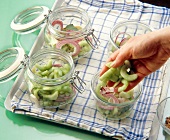 Woman filling cucumber slices in glass jar