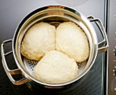 Close-up of three yeast dumplings in pot