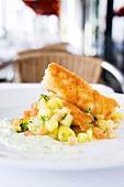 Crispy fried snapper with potato salad and green herb sauce on plate