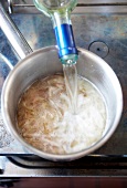White wine being poured into the pan with boiling shallot saute, step 1