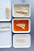 Cod, flour, egg, breadcrumbs and breaded fish in five different plates