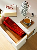 Open book with spectacles, tea cup and teapot on drawer table