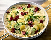 Potato omelette with kabanossi sausage and zucchini on serving dish