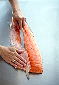 Person removing bones of salmon with tweezers
