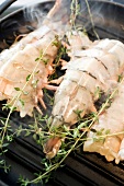 Close-up of grilled king prawns with sprigs of thyme in pan