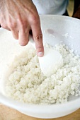 Gekochten Reis mit einem Löffel aus einer weißen Schale nehmen, Step 1