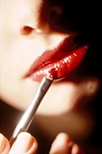 Close-up of woman applying red lipstick on lips