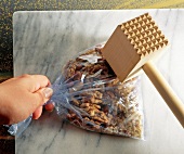 Smashing nuts in a transparent bag with meat tenderizer