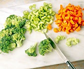 Carrots, celery and broccoli cut into small pieces on cutting board