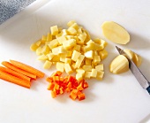 Carrots and potatoes cut with knife on cutting board