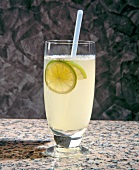 Lemon punch with slice of lime and straw in glass