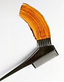 Close-up of comb used for applying hair colour and golden streaks on white background