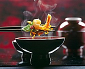 Deep-fried curried shrimp with vegetables in china bowl with chopsticks