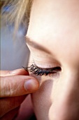 Close-up of woman sticking artificial eyelashes on her eyes