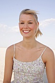 JenniferBlonde Frau mit Zopf und in geblühmten Top am Strand lacht