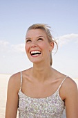 Portrait of beautiful woman in floral pattern dress standing on beach, smiling