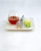 Asian dressing in glass with whisk and salad leaf