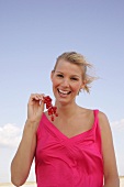 Blonde woman holding a branch of red currants in hand, smiling