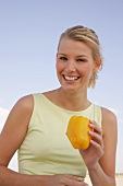 Jennifer Frau am Strand hält eine gelbe Paprika in der Hand