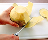 Peeling rutabaga with knife on cutting board