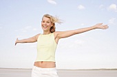 Happy woman with windswept hair smiling with arms outstretched