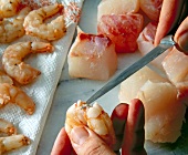 Pieces of fish fillet and shell of king prawns removed with knife